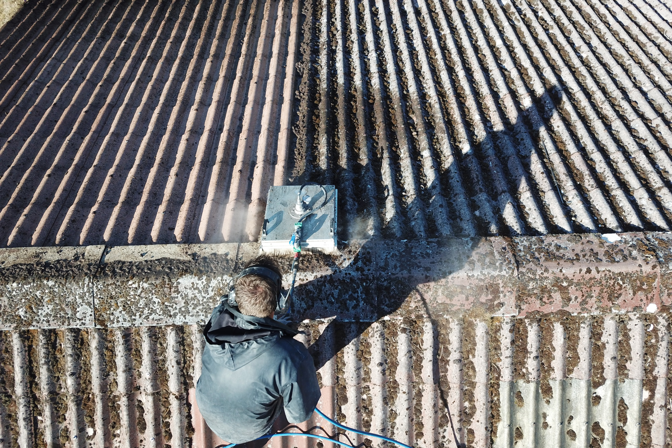 Image d'un technicien qui nettoie une toiture lors d'un contrat d'entretien