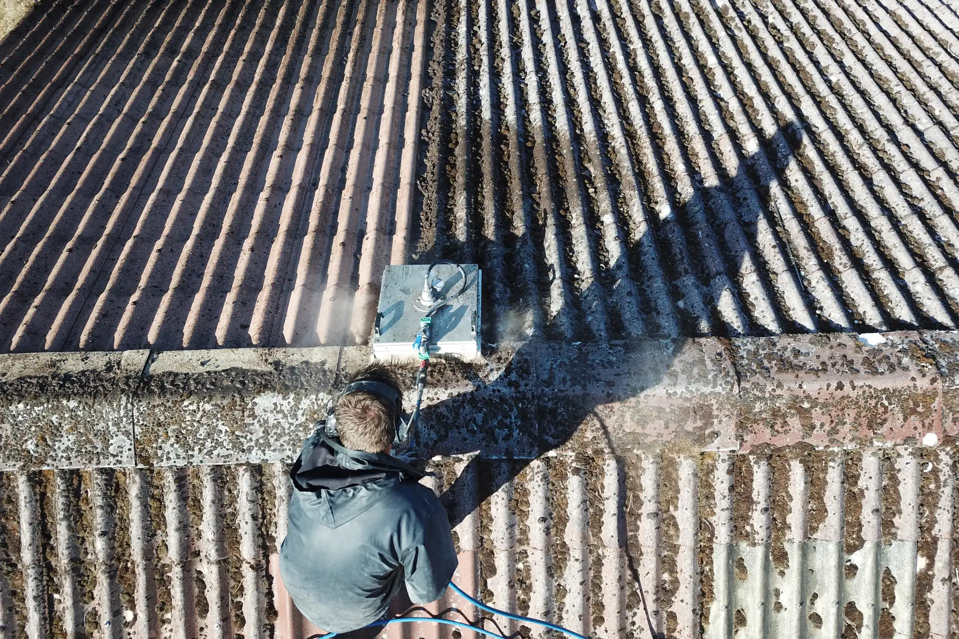 Image d'un technicien qui nettoie une toiture lors d'un contrat d'entretien