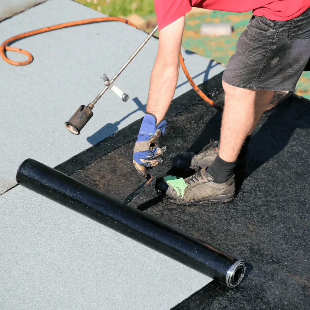 Professionnel travaillant sur un toit pour la mise en place d'un revêtements d'étanchéité d'un toit terrasse