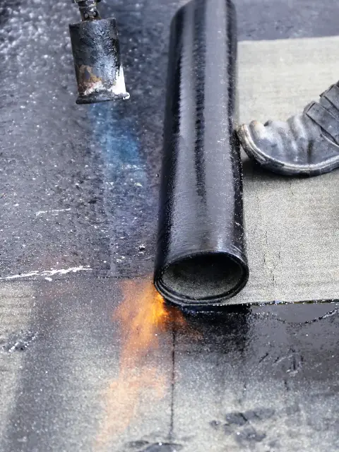 homme faisant l'étanchéité d'un toit terrasse avec un chalumeau